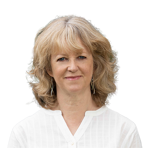 Woman with wavy blonde hair in a white shirt, smiling gently at the camera.