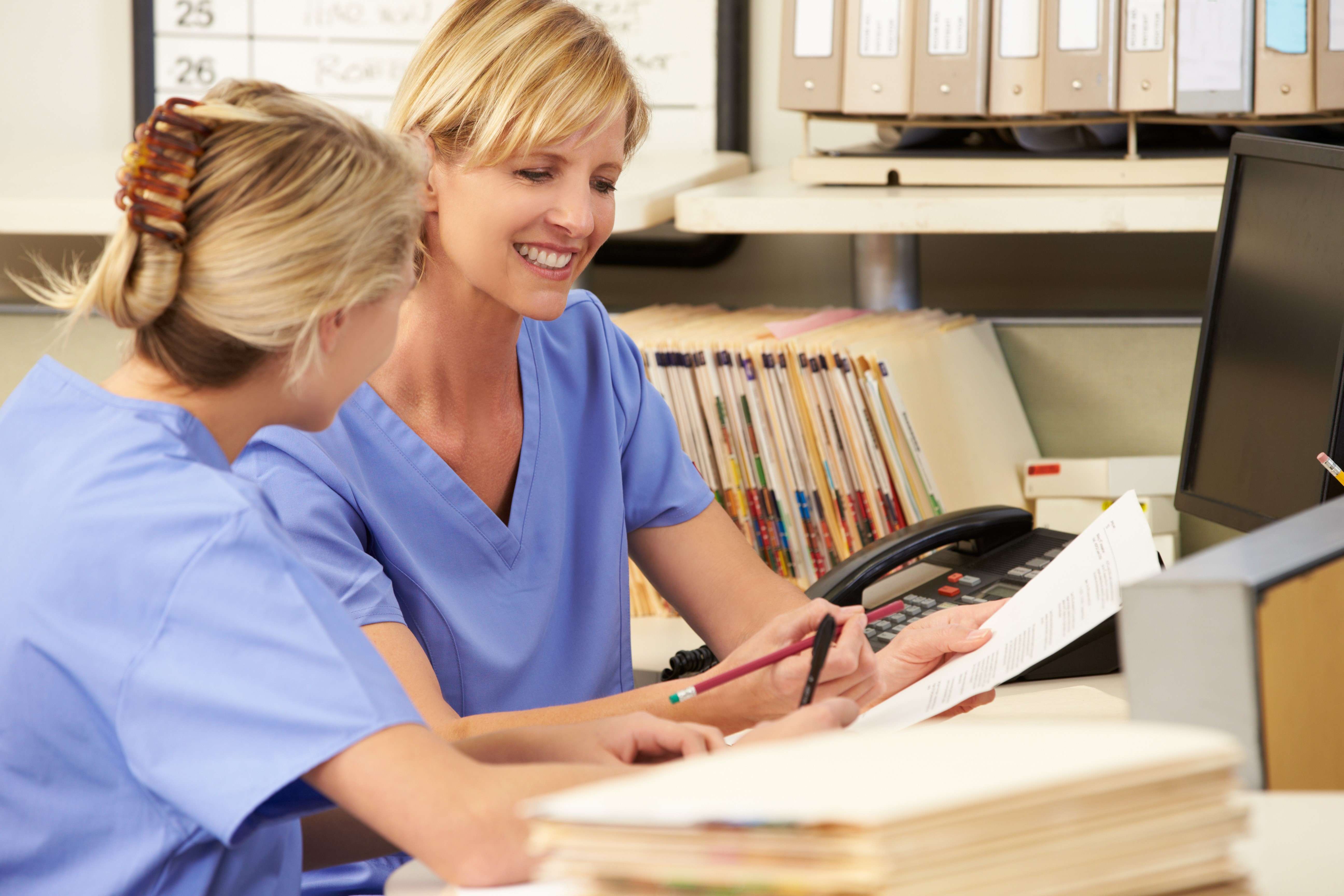 Two health professionals sit at a laptop