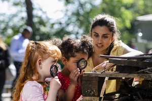Image of female teacher with children using magnifying glasses