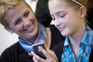 woman and girl looking at mobile phone