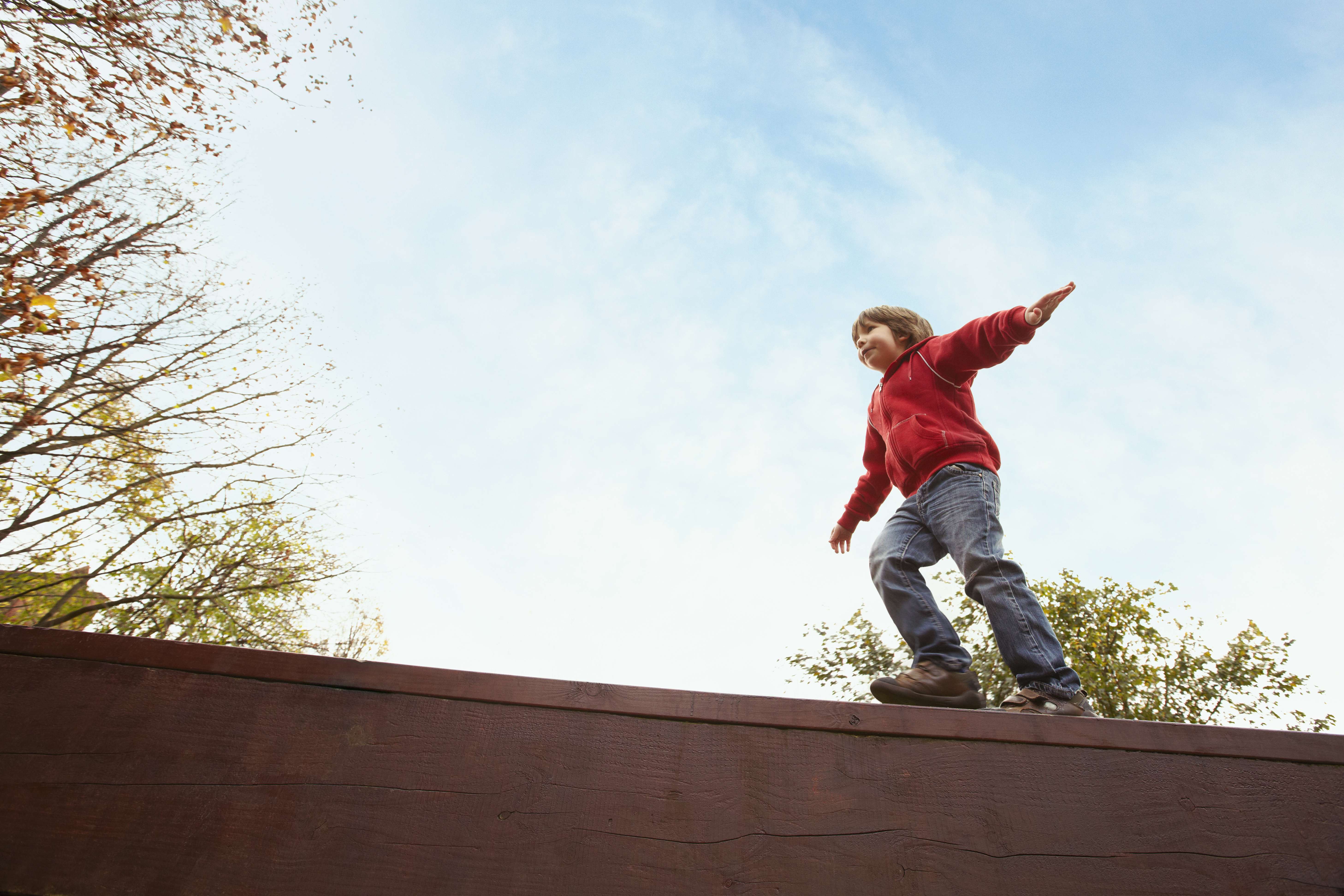 Young boy walking along the top of a wall