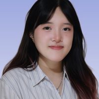 Portrait of a smiling woman with long dark hair, striped button-up shirt and necklace against a soft lavender background.