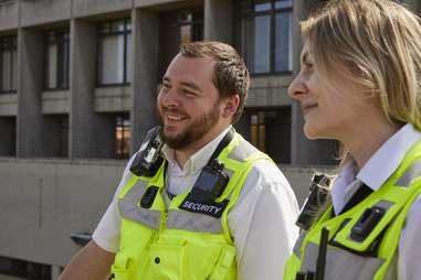 Two people in security high-vis jackets outside