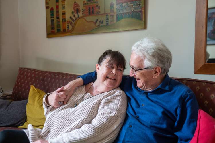 A man and a woman sitting together on a maroon sofa