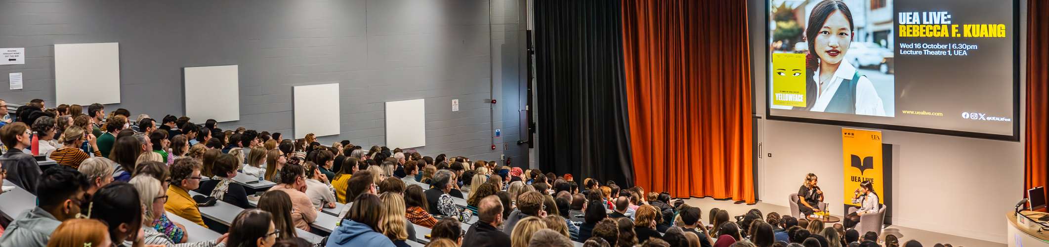 A lecture theatre of people watching an author speak.