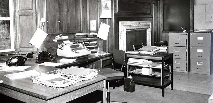 A black and white photo of an old office with desks and a typewriter.