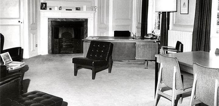 A black and white photo of a room with chairs and desks.
