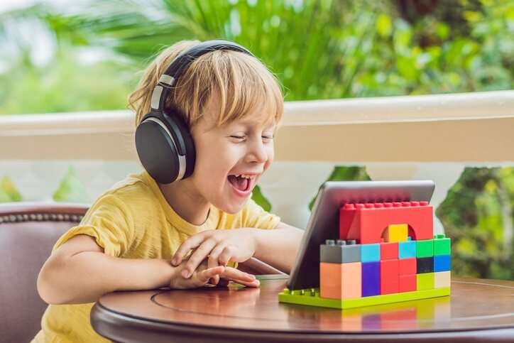 Young boy wearing headphones watching and laughing at his tablet