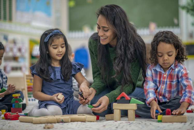 Female teacher teaching nursery children about shapes