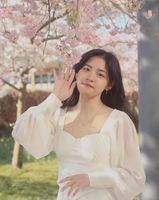 Girl wearing a white dress underneath a cherry blossom tree