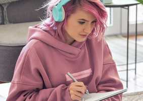 student wearing headphones writing on notepad
