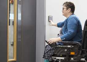 A wheelchair user uses a push pad to open a powered door
