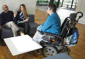 A wheelchair user is in conversation with two colleagues
