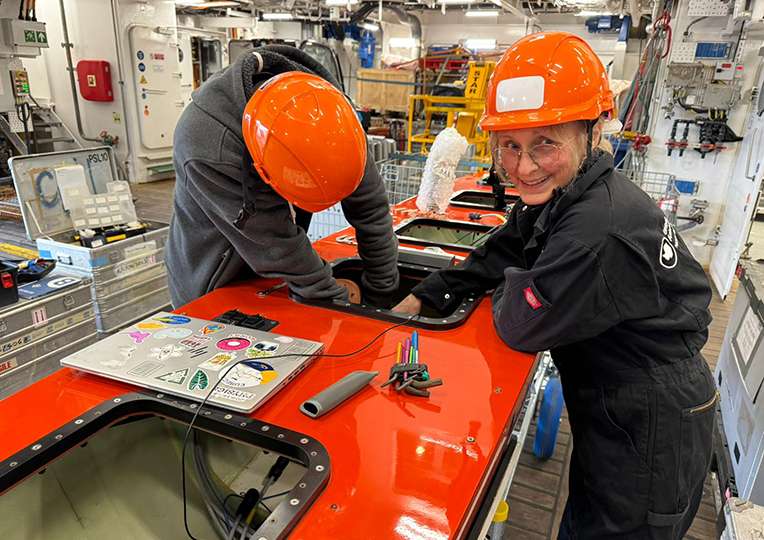 A man and a woman build an autonomous surface vessel.