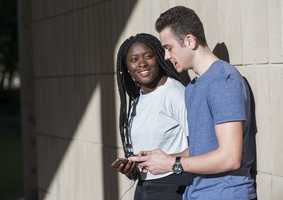 Two students leaning against a wall