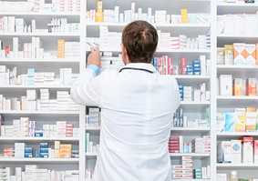 Pharmacist looking at shelves of medicine