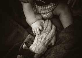 Elderly person and baby holding hands