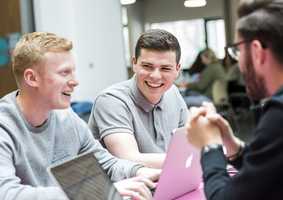 students in UNIO cafe smiling and using laptops