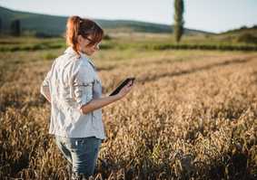 woman in field looking at apparatus tablet