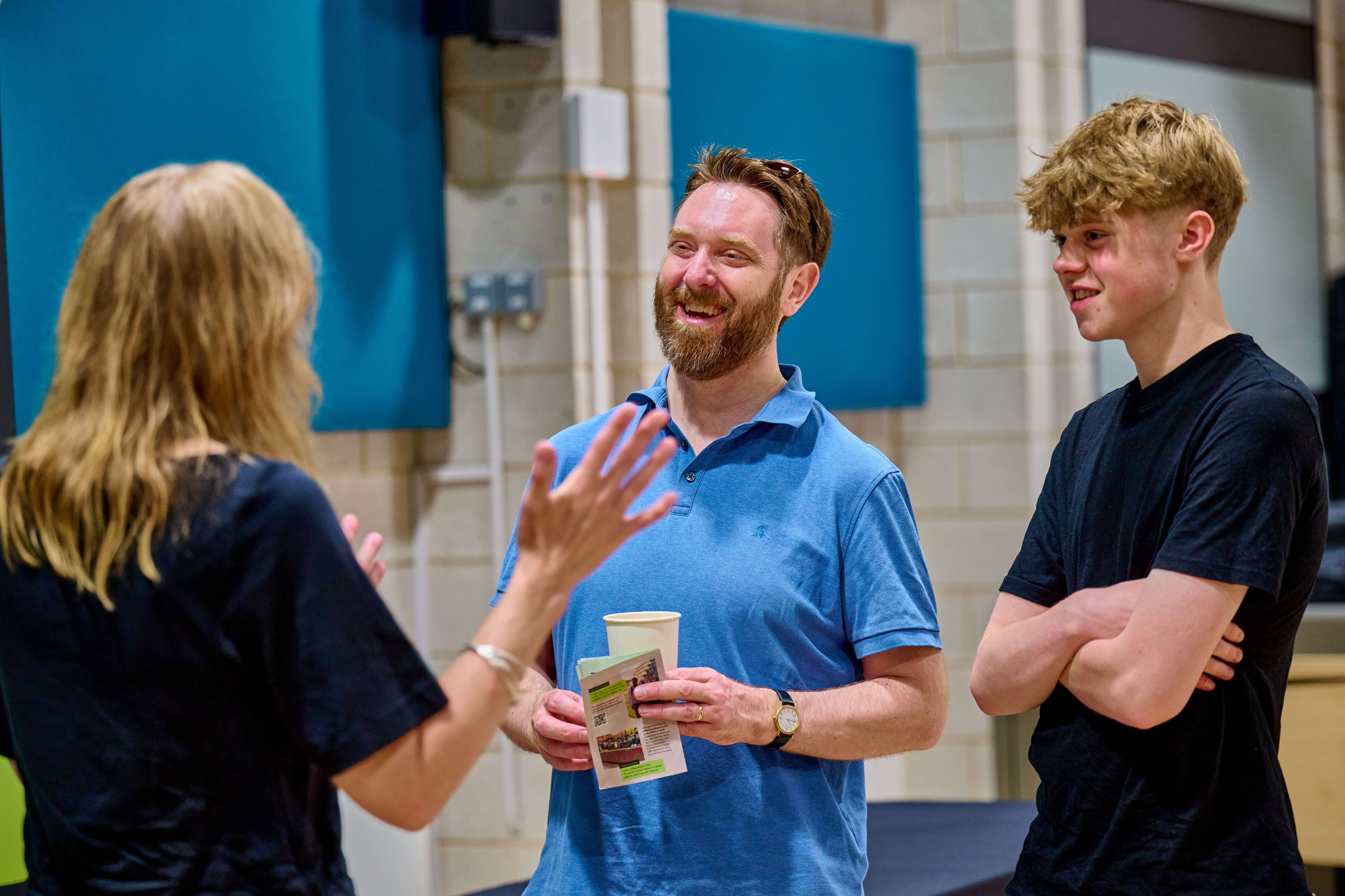 Two people speak to a lecturer.