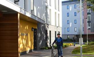 student-walking-past-accommodation-block-with-bicycle_26107.jpg
