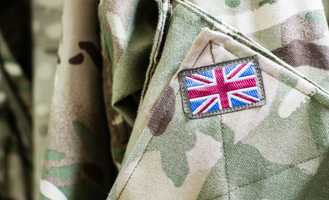 Close-up of a camouflage military uniform with a Union Jack patch on the sleeve, symbolizing British armed forces.