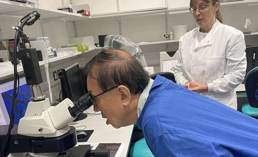 Dr KeeWee Tan looking into a research microscope alongside lab researcher Dr Rachel Hurst in Professor Colin Cooper’s prostate cancer research laboratory.