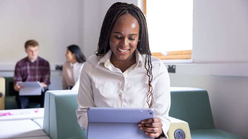 A student uses her computer. She is smiling.
