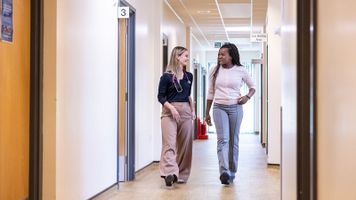 Two female clinicians walking down a corridor