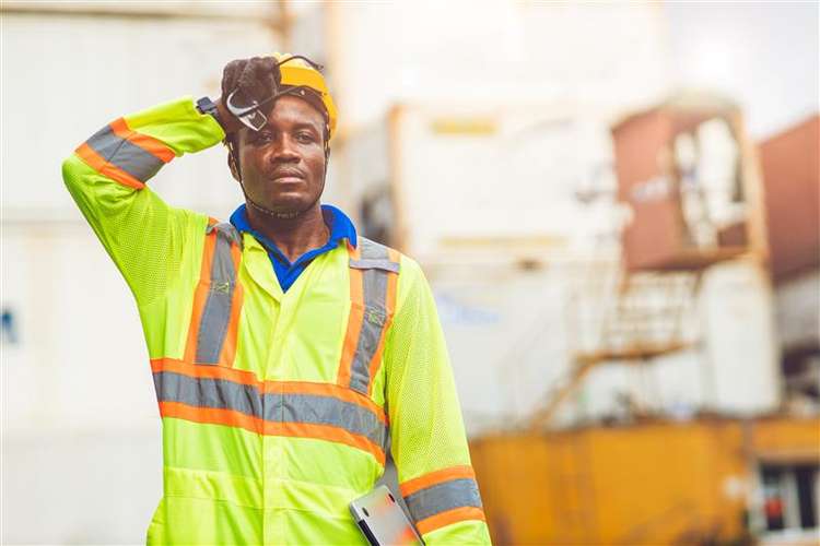 Construction man in high-vis wiping his brow