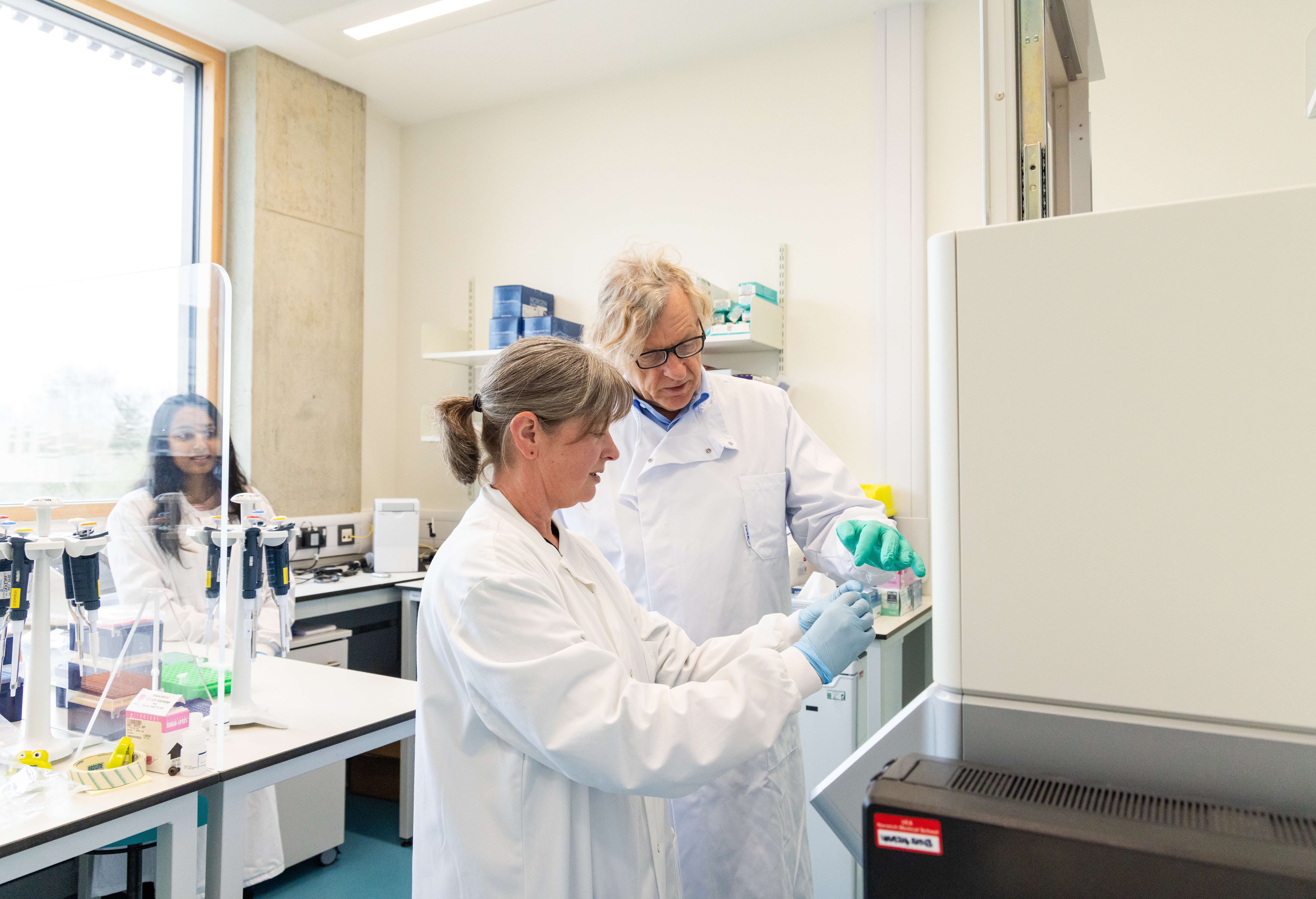 Researchers in lab coats collaborate in lab