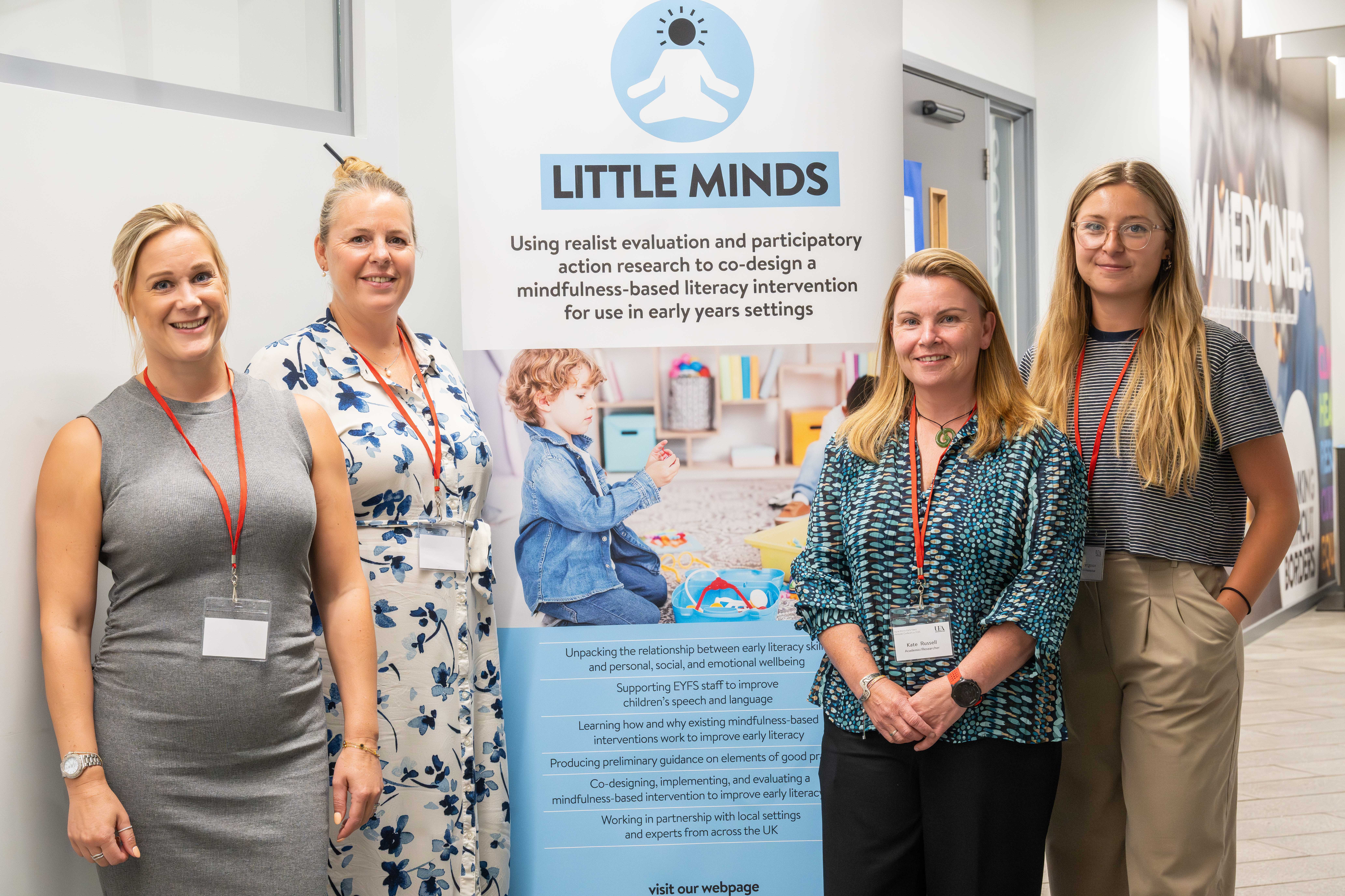 Four female researchers from the Little Minds team with a banner about the research