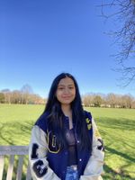 Zafirah in a sunny field smiling wearing a football jersey, black top and jeans